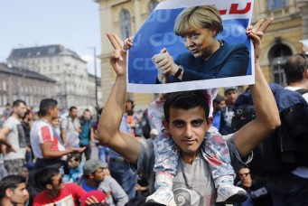 Man holds poster of German Chancellor Angela Merkel during march of refugees fleeing Hungary