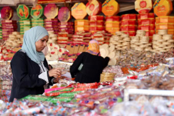 A woman buys traditional handmade sweets at a street market ahead of Mawlid al-Nabi, the birthday of Prophet Mohammad, in Sayeda Zainab neighbourhood in Cairo, Egypt, as sellers and customers all say prices of raw materials have increased due to the currency crisis, leading to a decrease in demand, September 24, 2023. REUTERS/Mohamed Abd El Ghany